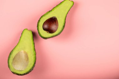 Tohumlu ve tohumsuz yeşil yarım avokado, pembe üst görünüm