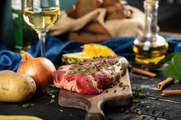 Carne cruda en un tablero de madera con hierbas y especias — Foto de Stock