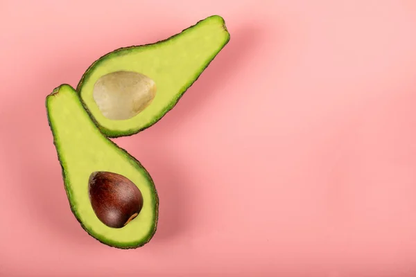 Groene halve avocado 's geïsoleerd op roze achtergrond, met en zonder zaad — Stockfoto