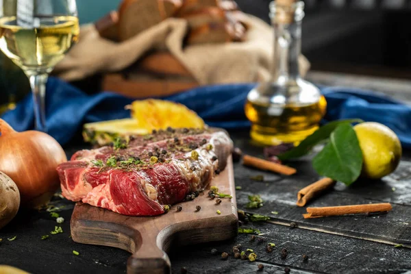 Carne cruda en un tablero de madera con hierbas y especias, limón y verduras — Foto de Stock