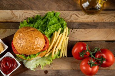 Hamburger, soğanlı rulo ve soslu kızarmış patates.