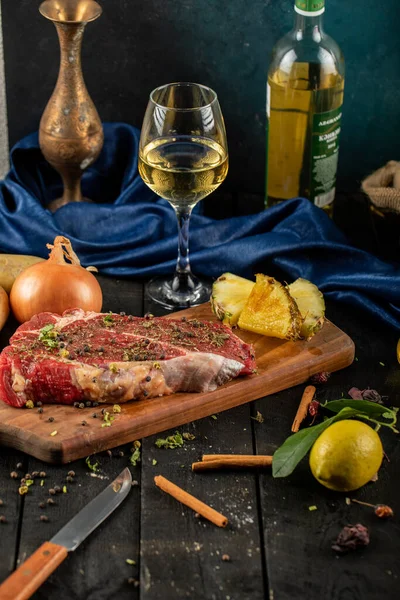 Carne cruda en una tabla de madera con hierbas y especias, servida con una copa de vino blanco — Foto de Stock