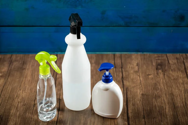 Hand sanitizers around in white containers in blue background, on a wooden table — Stock Photo, Image