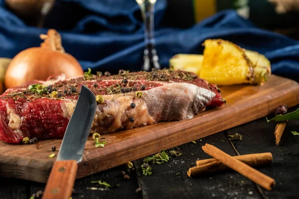 Rauw vlees op een houten plank met uien en ananasschijfjes — Stockfoto