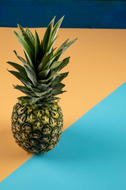 Turuncu mavi arka planda yeşil yapraklı ananas