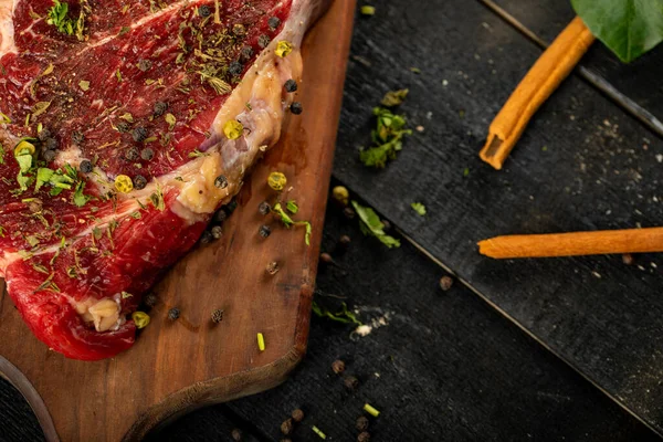 Rauw vlees op een houten plank met kruiden en specerijen, kaneelstokjes — Stockfoto