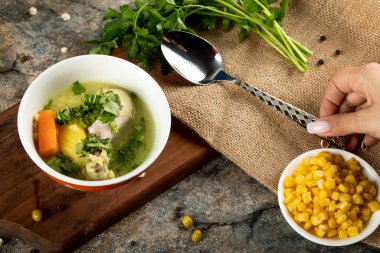 Baharatlı mısırla servis edilen sebzeli tavuk çorbası.