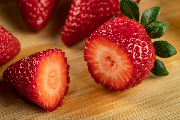 Rote, frische Erdbeeren in Stücke geschnitten auf einem Holzbrett — Stockfoto