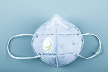 Mavi bir tıbbi maske mavi arkaplanda izole edilmiş.
