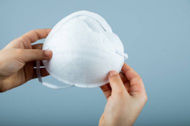 Beyaz, modern bir tıbbi yüz maskesi tutan bir el. 