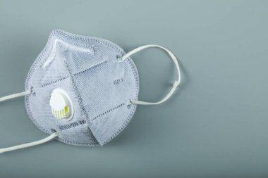 Mavi, modern bir tıbbi yüz maskesi mavi arka planda izole edilmiş.