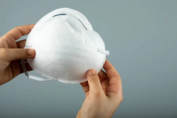 Дві руки тримають білу сучасну медичну маску для обличчя — стокове фото