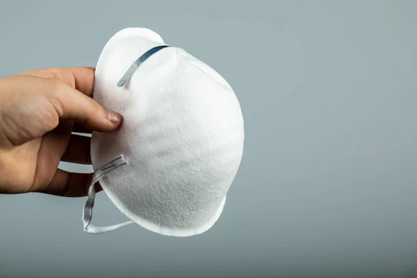 Segurando uma máscara médica moderna branca — Fotografia de Stock