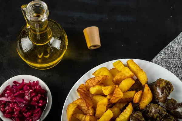 Gefrituurde aardappelen in wit bord geserveerd met gemarineerde voedingsmiddelen en olijfolie — Stockfoto