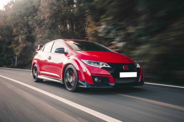 Sıcak bir yaz gününde kırmızı süper araba otoyolda turluyor.