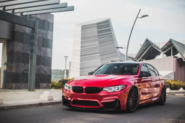 Boş şehir yollarında kırmızı model sedan, modern binalar boyunca, ön manzara