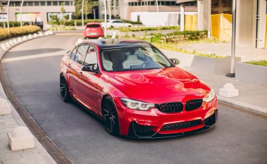 Kırmızı evrensel sedan bir yaz gününde şehir sokaklarında turluyor.