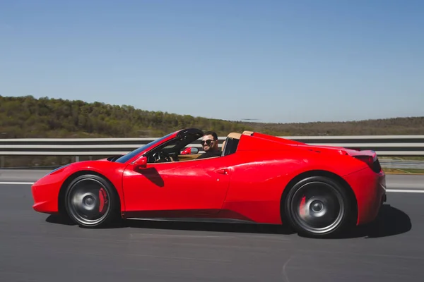 Voiture de sport rouge conduisant sur l'autoroute par une journée ensoleillée, vue de profil — Photo