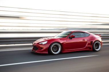 Köprüden geçen kırmızı şık spor araba, bulanık görüş.