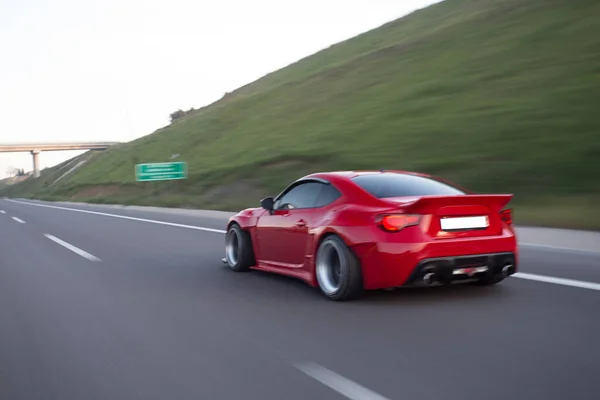 Rojo elegante deporte coche paisaje conducción a través de colinas —  Fotos de Stock