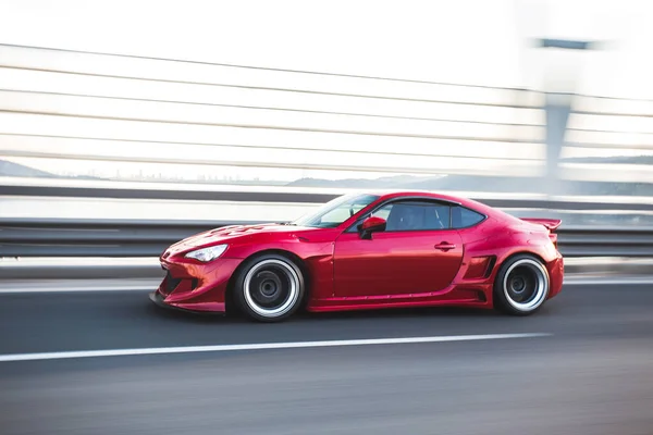 Red elegant sport car driving over the bridge — Stock Photo, Image