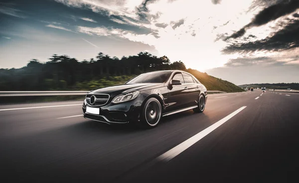 Siyah sedan güneşli bir günde dağlarda seyahat ediyor.