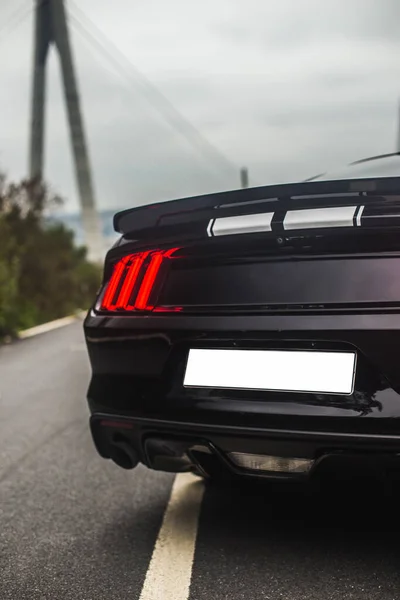 Terug rood xenon lichten van een zwarte auto, buiten, stormachtig weer — Stockfoto