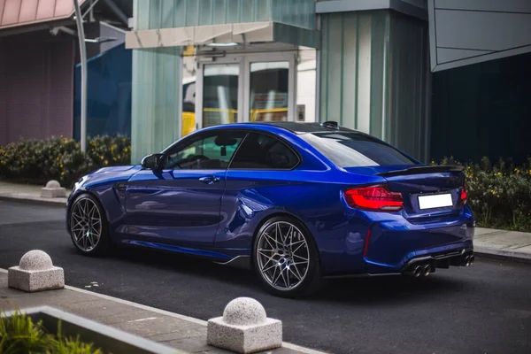 Blue sport sedan parked in front of a business center — Stock Photo, Image