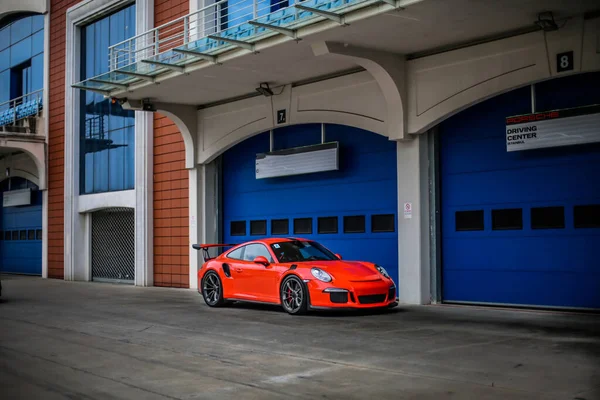 Coches de carreras de color naranja en la pista de rally frente a las puertas de un edificio —  Fotos de Stock