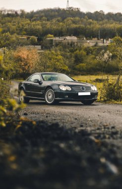 Tarlalarda siyah eski moda sedan, yeşil tarlalar boyunca manzara