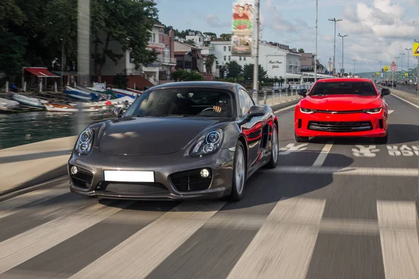 Supercarros vermelhos e pretos correndo nas ruas da cidade na cruz pedestre — Fotografia de Stock