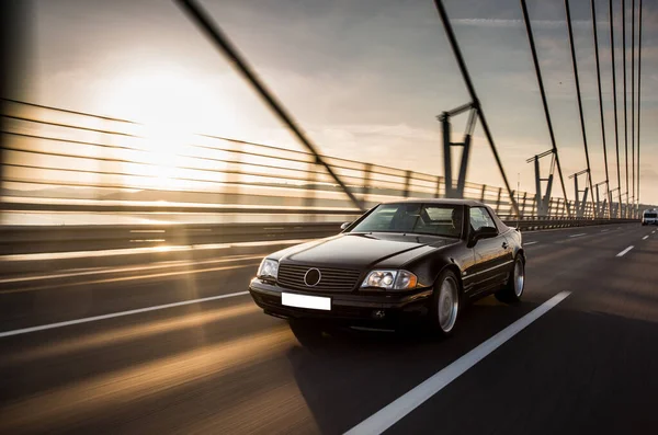 Un coche sedán vintage en el puente al atardecer — Foto de Stock