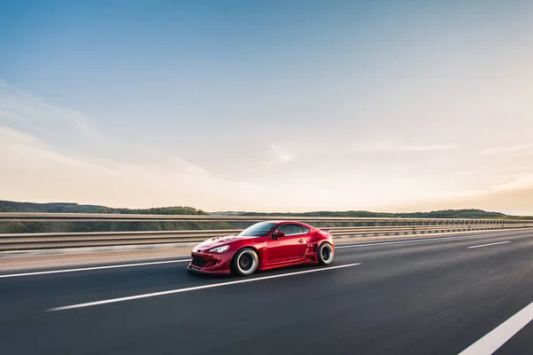 Güneşli bir günde otoyolda kırmızı yarış arabası