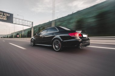 Yeni model siyah sedan şehir merkezindeki otoyolda, arkadan görüntüsü var.