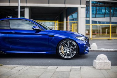 Dışarıdaki mavi sedan, lüks bir binanın önünde.