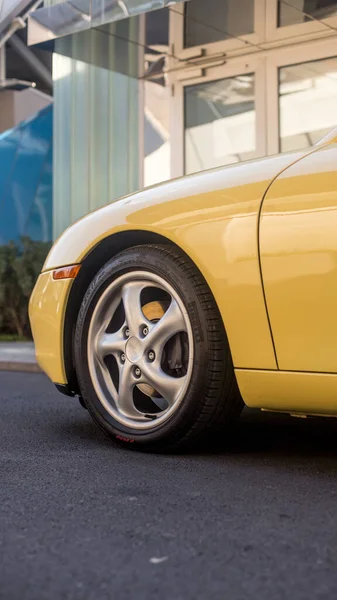 Rueda delantera y parachoques de un coche amarillo en la ciudad —  Fotos de Stock