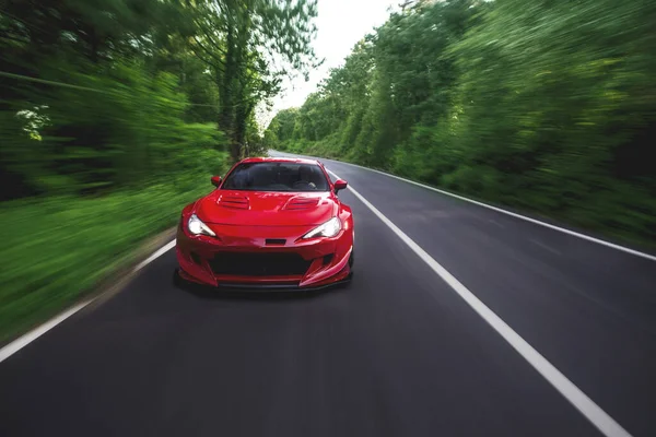 Superpower czerwony samochód wyścigowy na dysku krajobraz przez lasy deszczowe — Zdjęcie stockowe