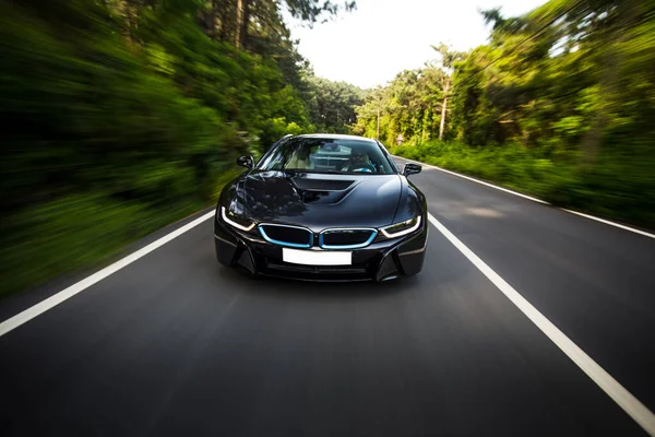 Wolno poruszający się czarny sedan na leśnej drodze — Zdjęcie stockowe