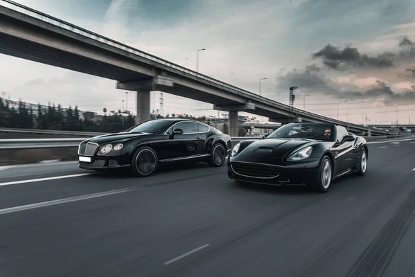 Dois carros pretos automobilismo corridas na estrada — Fotografia de Stock