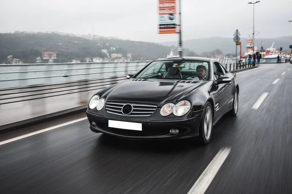 Modelo negro coche velocidad movimiento en el tiempo brumoso en la orilla del mar — Foto de Stock