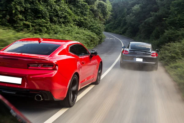 Czerwone i czarne samochody sportowe przejeżdżające obok siebie, prędkość jazdy, widok z tyłu — Zdjęcie stockowe
