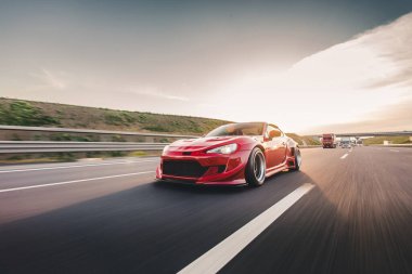 Güneşli bir günde otoyolda kırmızı yarış arabası, ekolojik sürüş