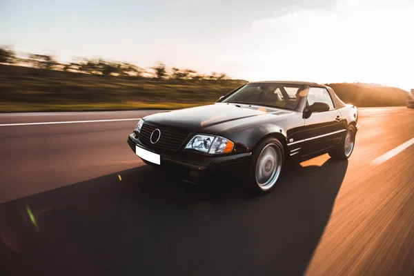 Güneş ışığında, orman yolunda kırmızı bir vintage sedan. — Stok fotoğraf