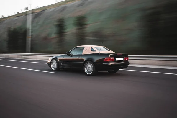 Une berline vintage rouge sur la route de la ville le soir — Photo