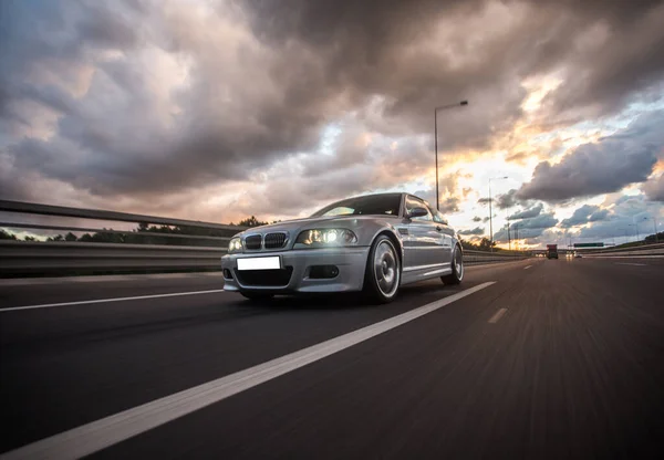 Silver racecar rushing in the fields under heavy clouds — Stock Photo, Image