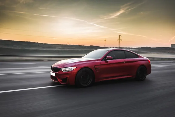 Red sport cab in a countryside area in the sunset, white xenon lights on — Stock Photo, Image