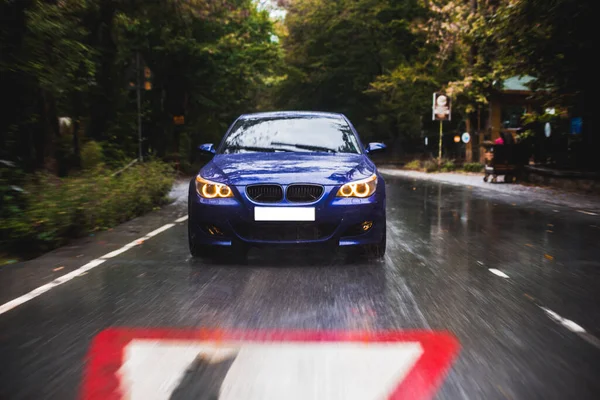 Kék autó nagy sebességű meghajtó az erdei úton egy viharos esős napon — Stock Fotó