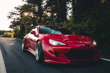 Otobanda kırmızı yarış arabası Ormanın gölgesinde panoramik manzaralı