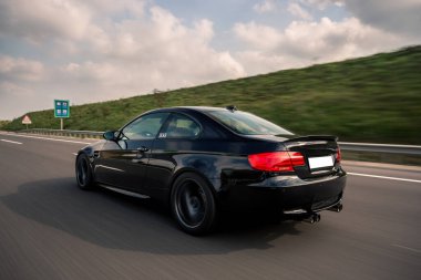 Dağlık arazide siyah turbo motor spor araba, arkadan görüş.