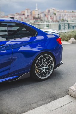 Mavi sedan park yeri, arka tekerlek ve kapı manzarası.